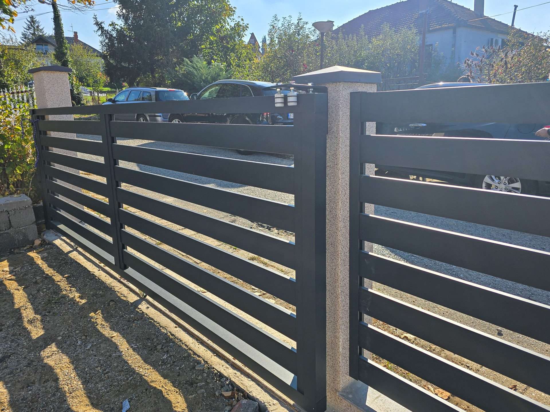 Crna aluminijumska ograda sa horizontalnim lamelama u urbanom susedstvu - parking ispred kuće